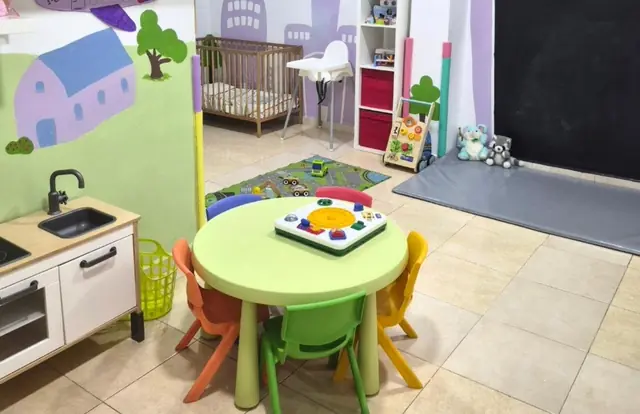 Rincón con cocinita de juguete y mesa redonda con sillas pequeñas