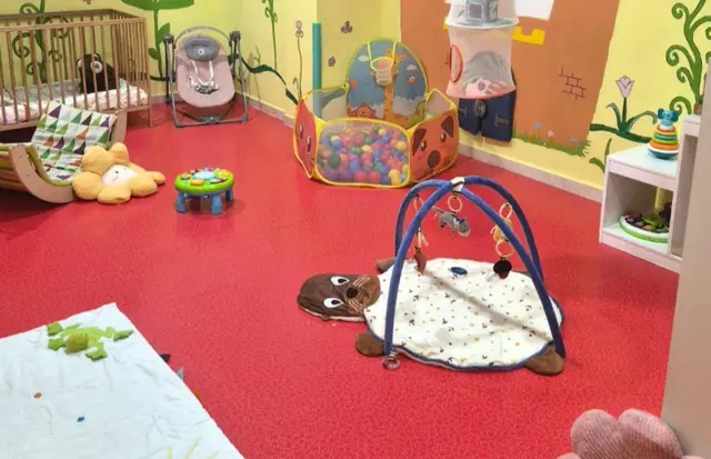 Sala de bebés con suelo blando, gimnasio de actividades y cunas